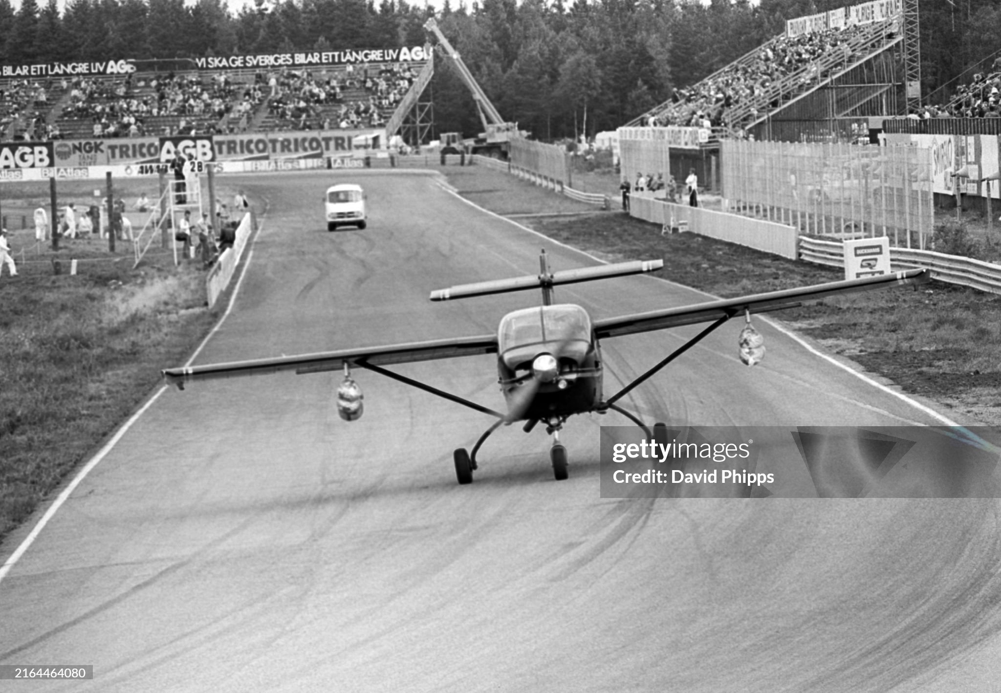 An aeroplane lands on the main straight shortly before the drivers parade at the Grand Prix of Sweden in Anderstorp on 13 June 1976. 