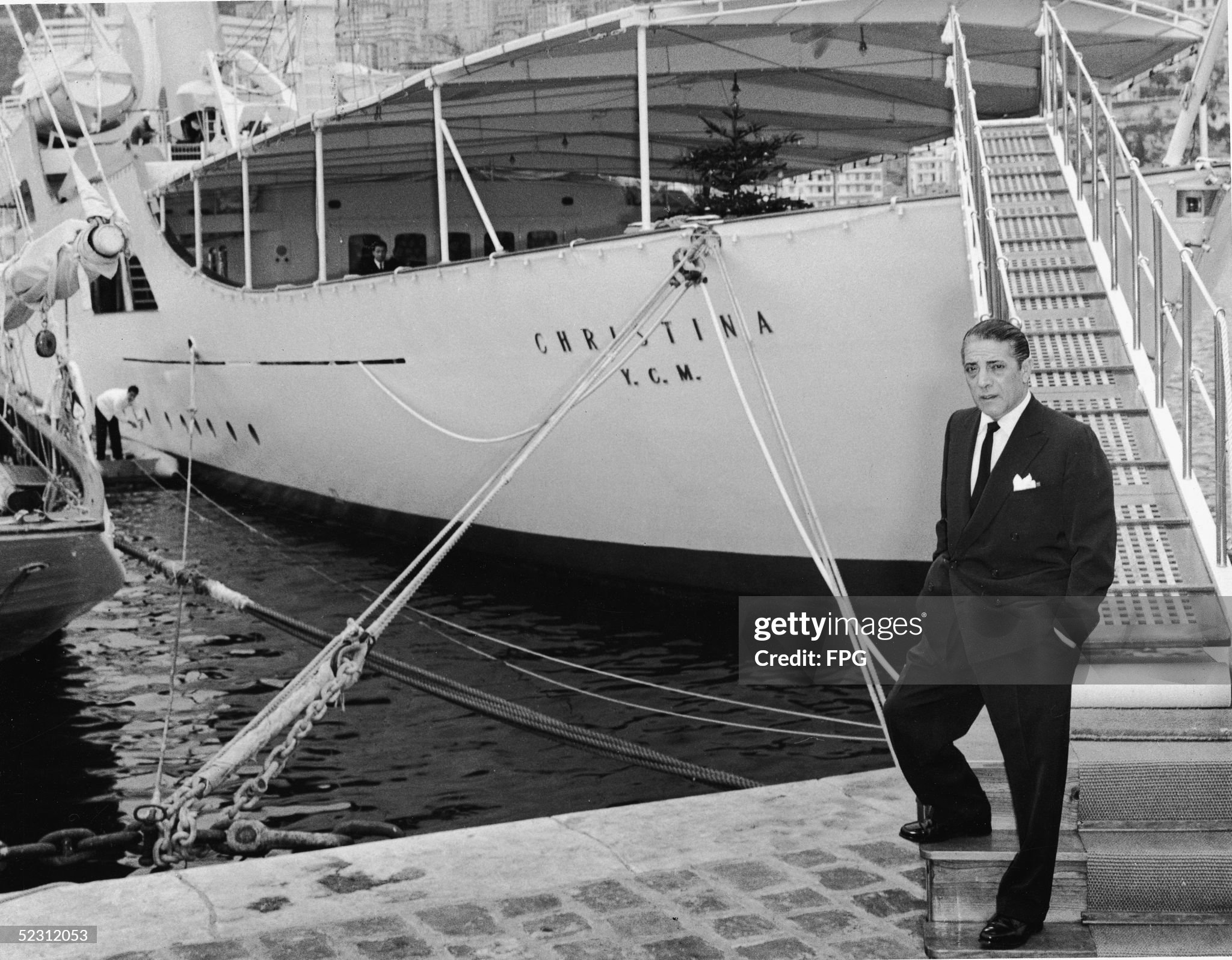 Greek shipping magnate Aristotle Onassis (1906 - 1975) stands on a dock in front of his private yacht, the 'Christina', in mid 1950s. 