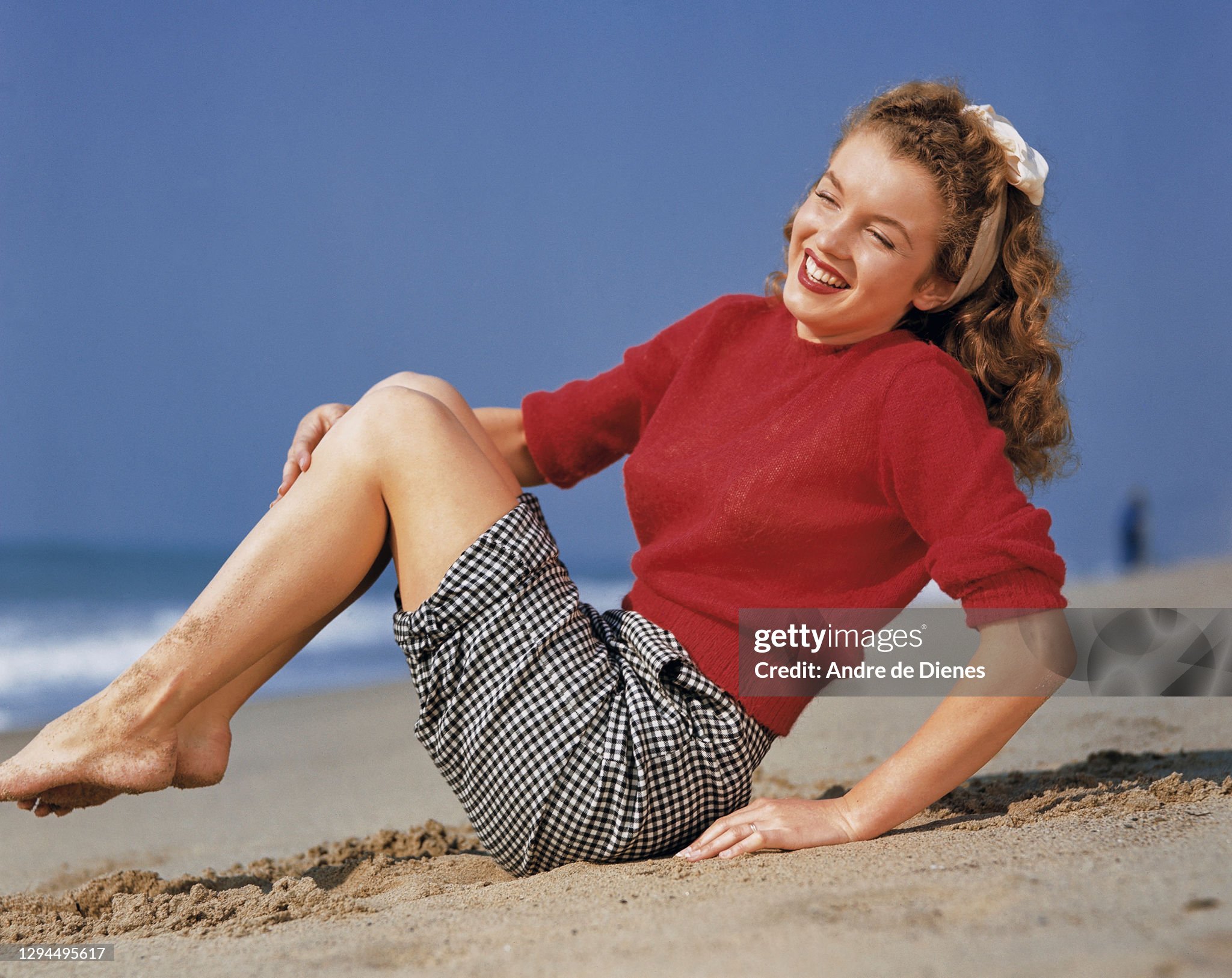 Marilyn Monroe (born Norma Jeane Mortenson, 1926 - 1962) in a red sweater and checkered trousers, as she poses at Zuma Beach's Paradise Cove, California, in 1945. 