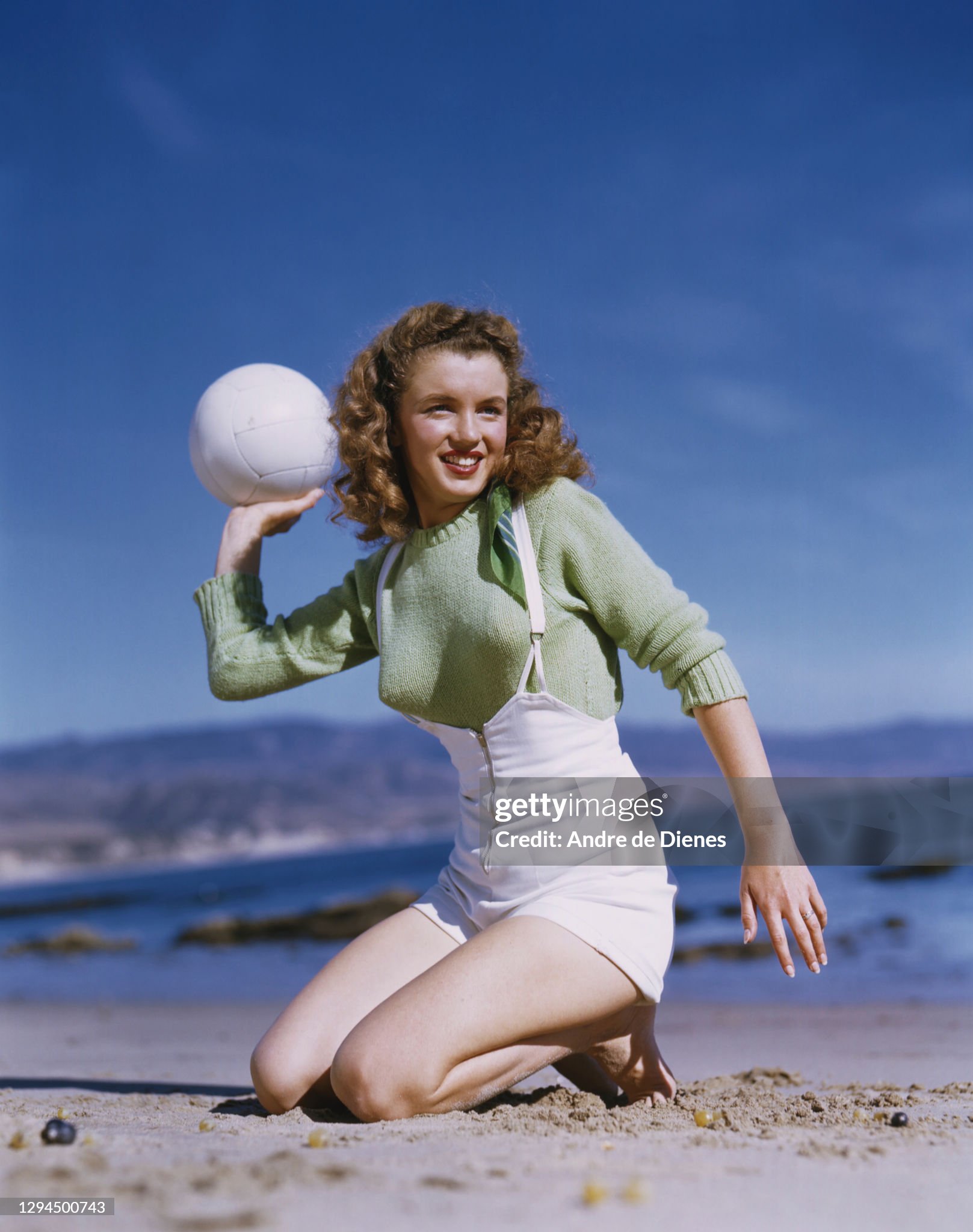 Marilyn Monroe (born Norma Jeane Mortenson, 1926 - 1962) in a red sweater and checkered trousers, as she poses with volleyball at Zuma Beach's Paradise Cove, California, in 1945. 