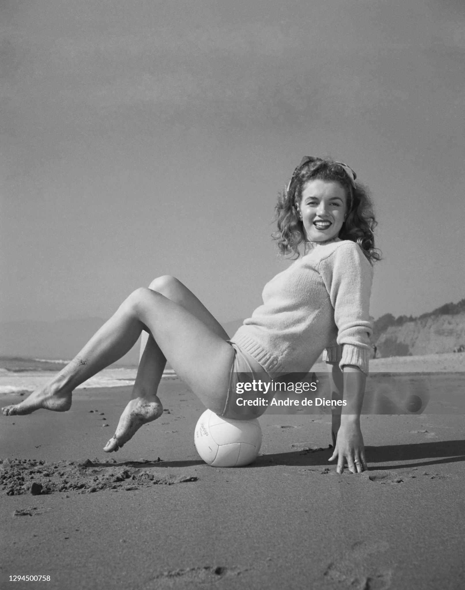 Marilyn Monroe (born Norma Jeane Mortenson, 1926 - 1962) in a red sweater and checkered trousers, as she poses balancing on a volleyball at Zuma Beach's Paradise Cove, California, in 1945. 