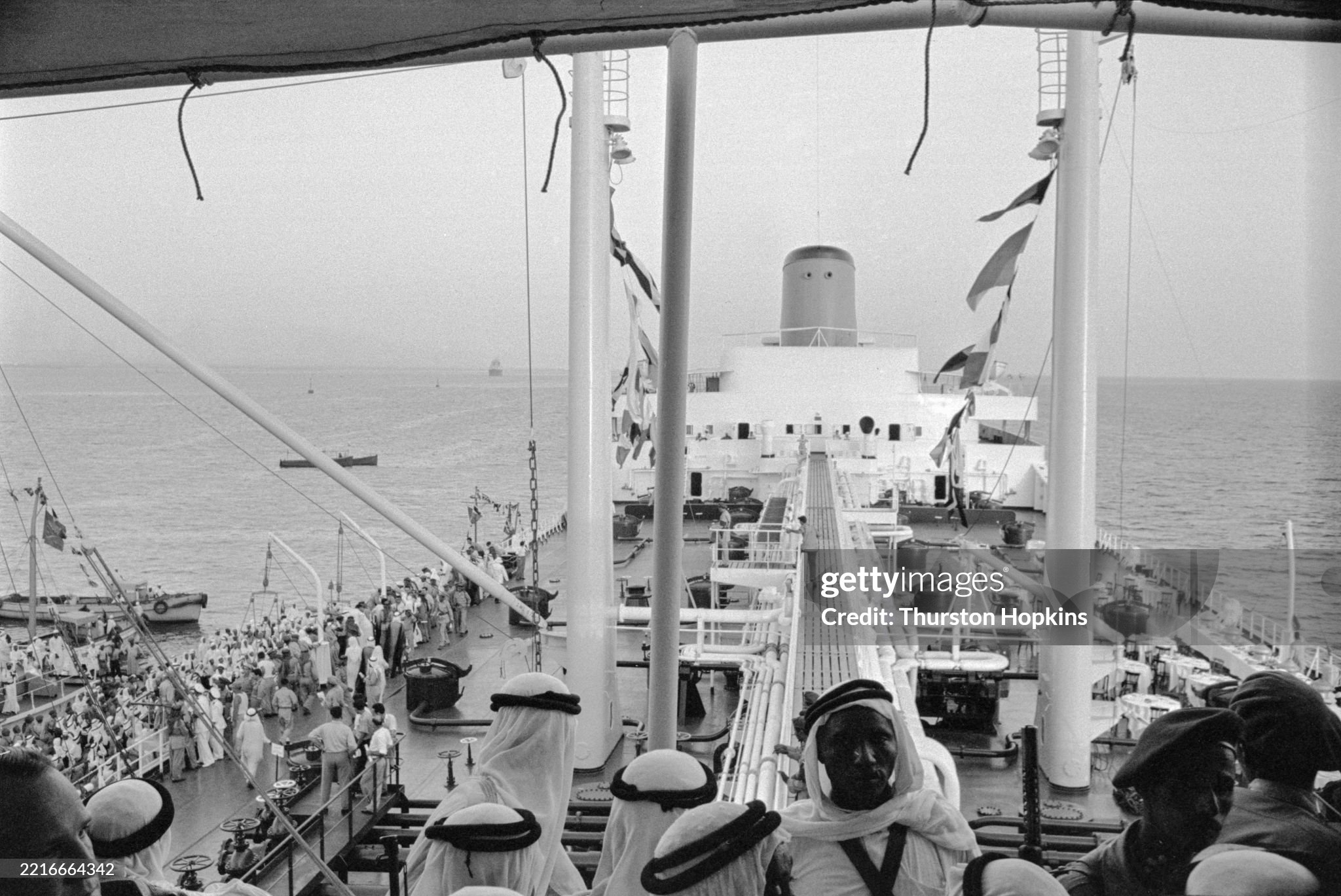 View across the deck of the oil tanker Al-Malik Saud Al-Awal where Greek shipping magnate Aristotle Onassis was hosting a party in the bay off Jeddah, Saudi Arabia, in July 1955. Guests are shown boarding the tanker at left. Onassis was celebrating his tanker being the first to fly the flag of Saudi Arabia. The 48,000-ton Al-Malik Saud Al-Awal was then the largest oil tanker in the world.