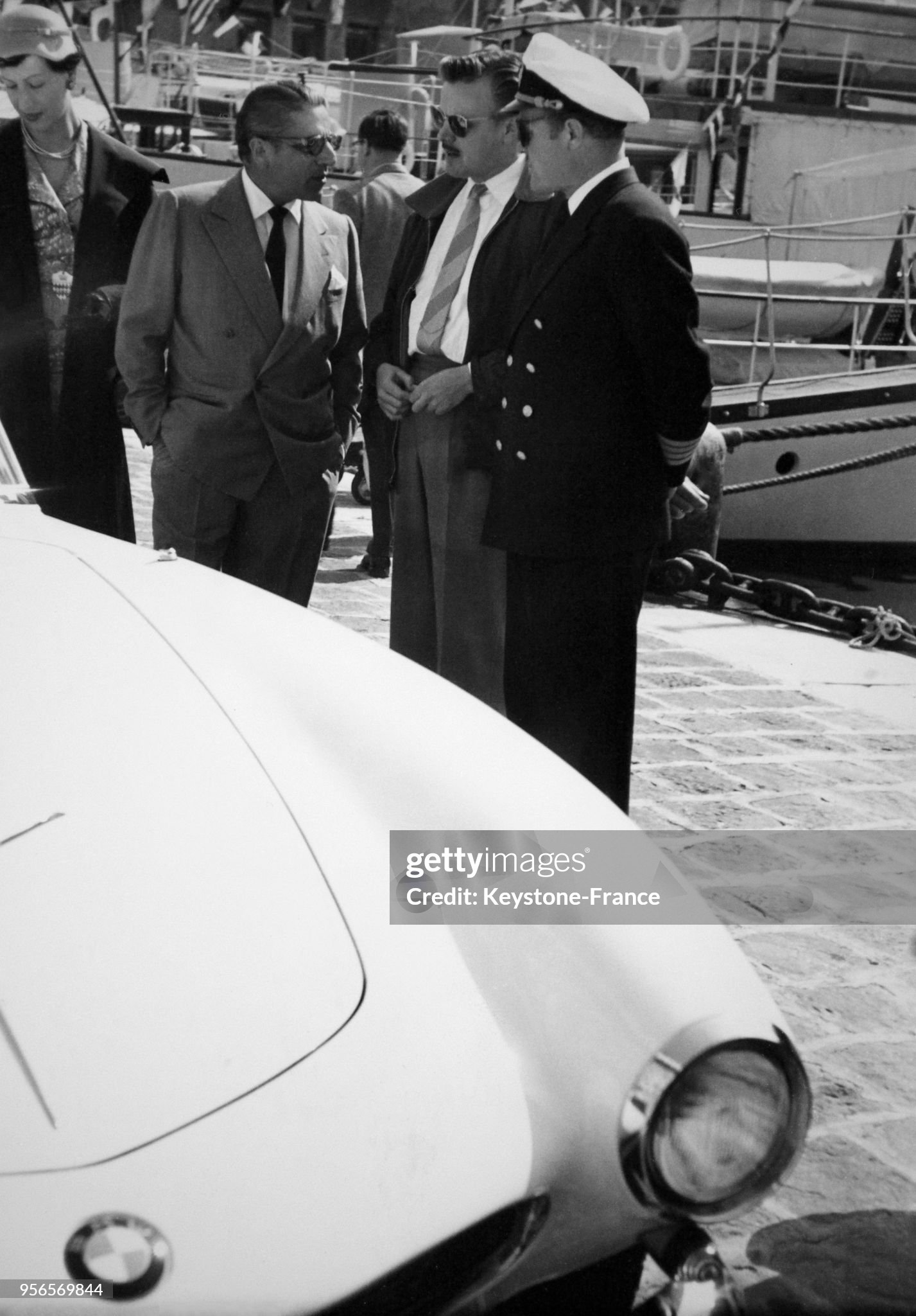 Aristotle Onassis and the captain of his ship look at the new BMW 507 parked in the port of Monaco on April 21, 1956. 