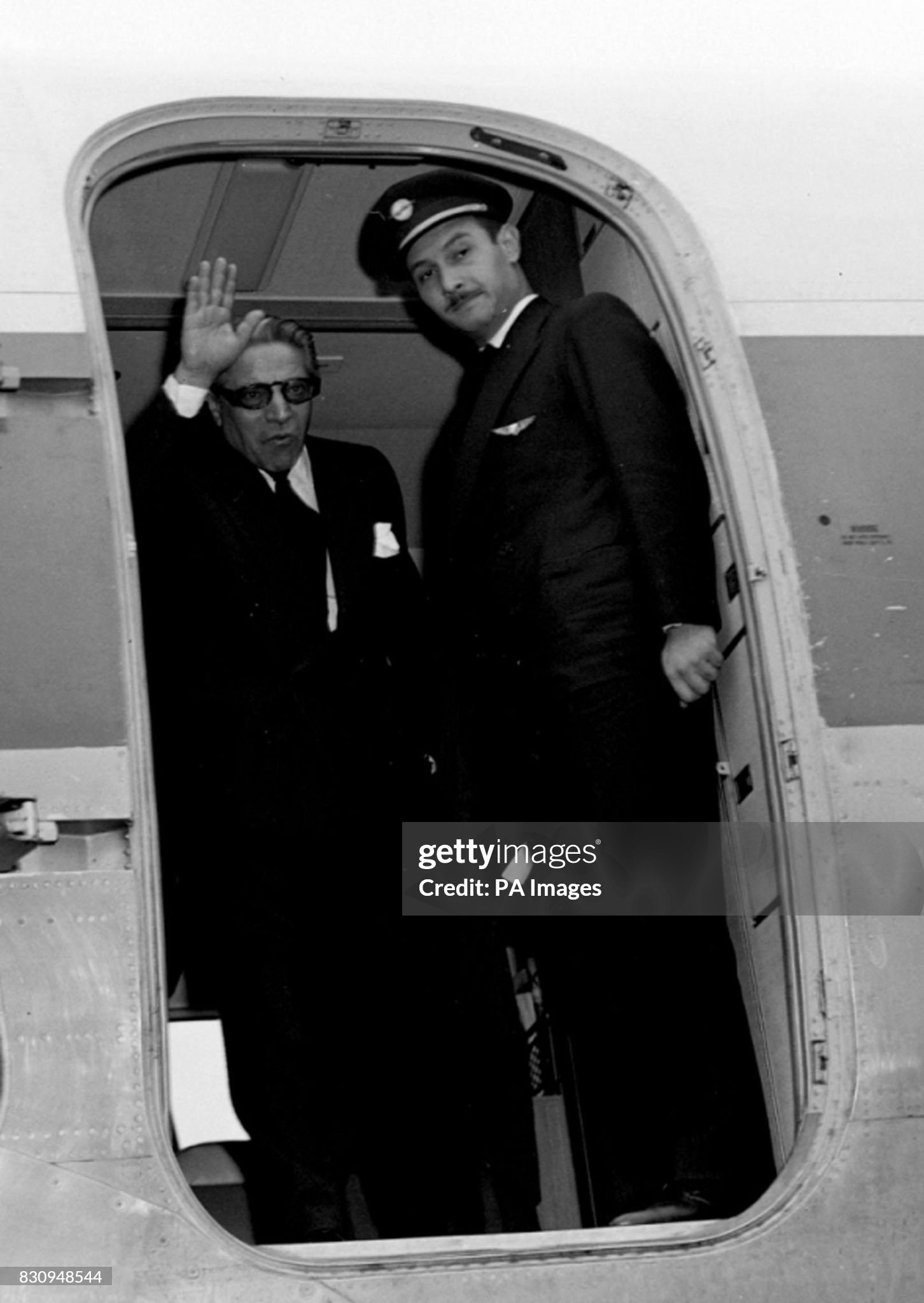 Aristotle Onassis waves from a DC 6B plane of his Olympic Airline before leaving London with Sir Winston and Lady Churchill for Marrakesh, Morocco, on 12 January 1959. 