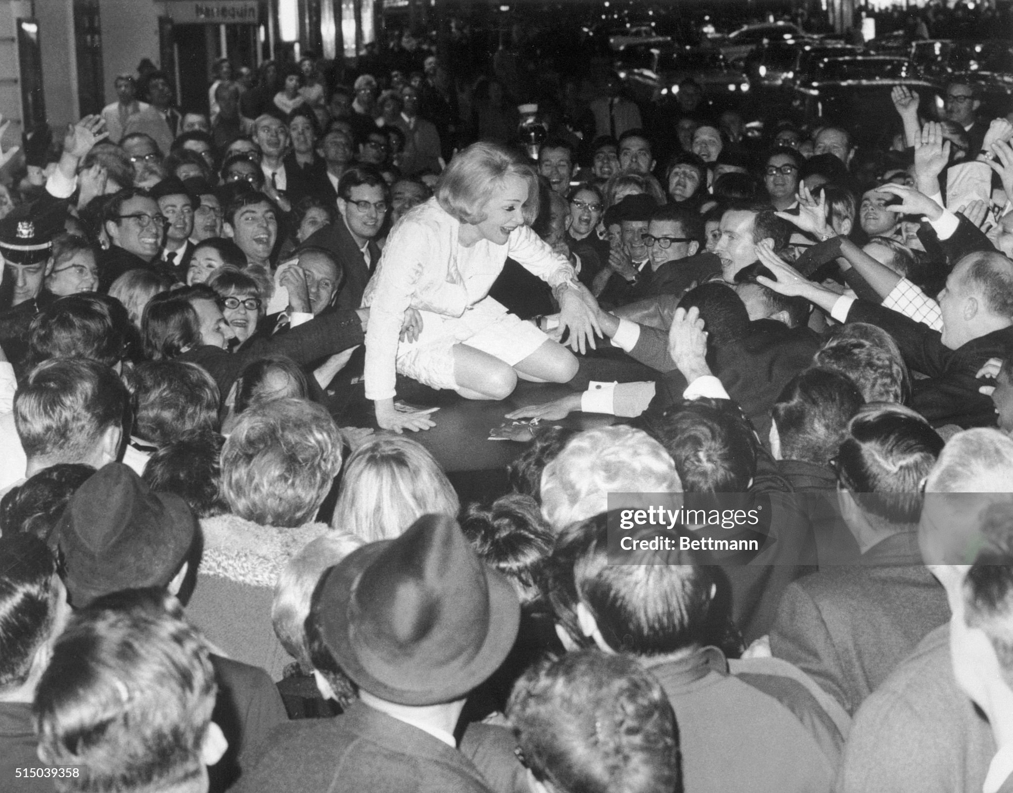 New York, 06 November 1967: Marlene Dietrich happily climbs atop her waiting limousine as protection from wildly enthusiastic fans outside the Lunt-Fontanne Theater where she is starring in a one woman show. 