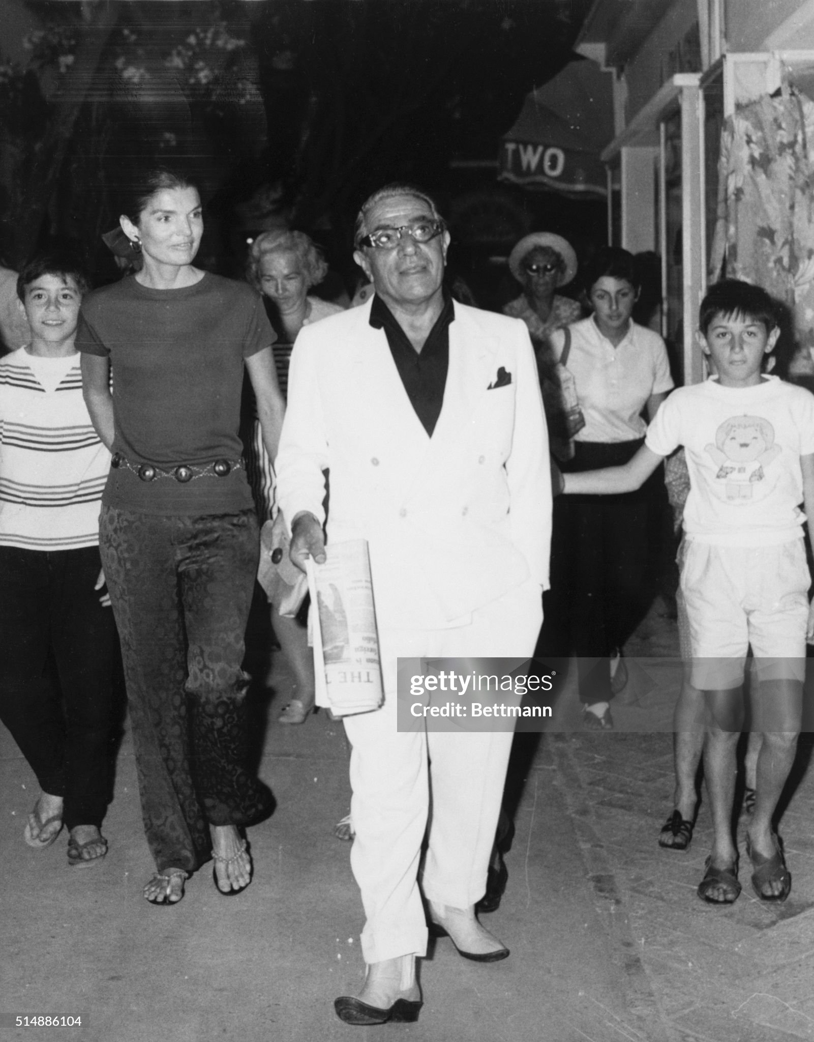 Jackie and Aristotle Onassis walk through the streets of a town on Capri, followed by local residents on 23 June 1969. 