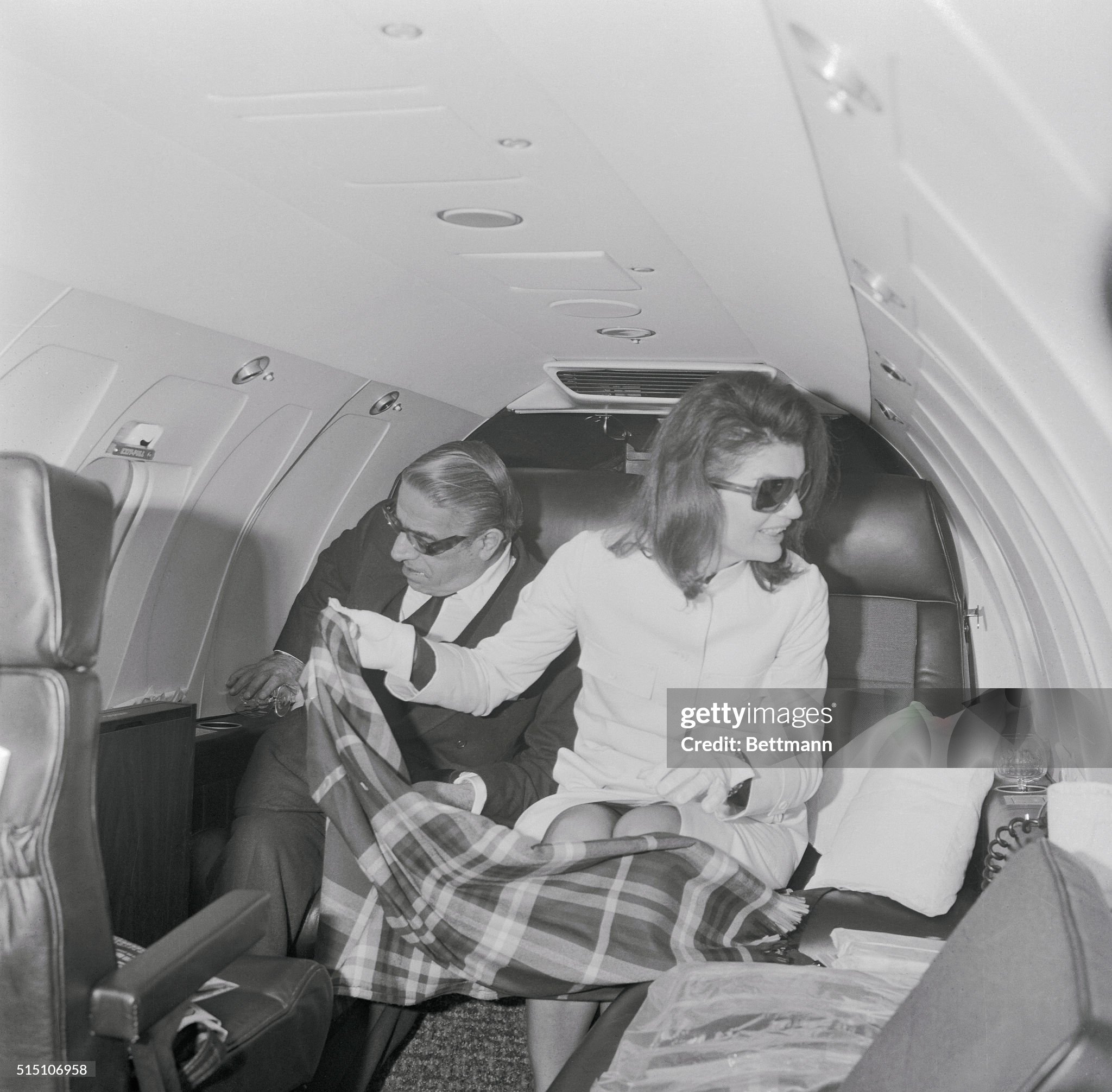 Jacqueline Onassis protects her husband Aristotle Onassis and herself from the cold with a lap rug, as they sit in their private jet in March 1971.