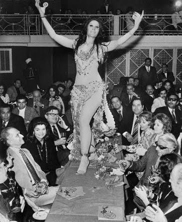 With husband Ari, Jackie Onassis takes in some belly dancing on the table at Cairo, Egypt, in 1973. Jackie didn’t take as well to a belly dancer as she did the Nile. Ari liked it.
