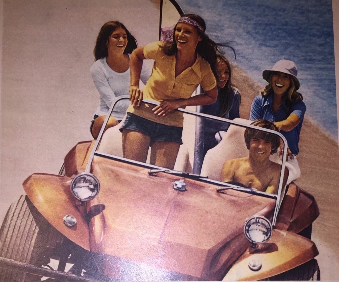 A man and four girls in a Dune Buggy on the beach.