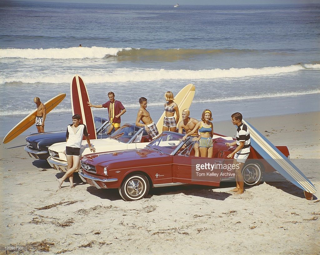 Vintage surfers and cars on the beach.