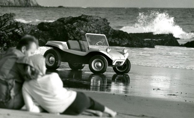 A Dune Buggy and a couple on the beach.