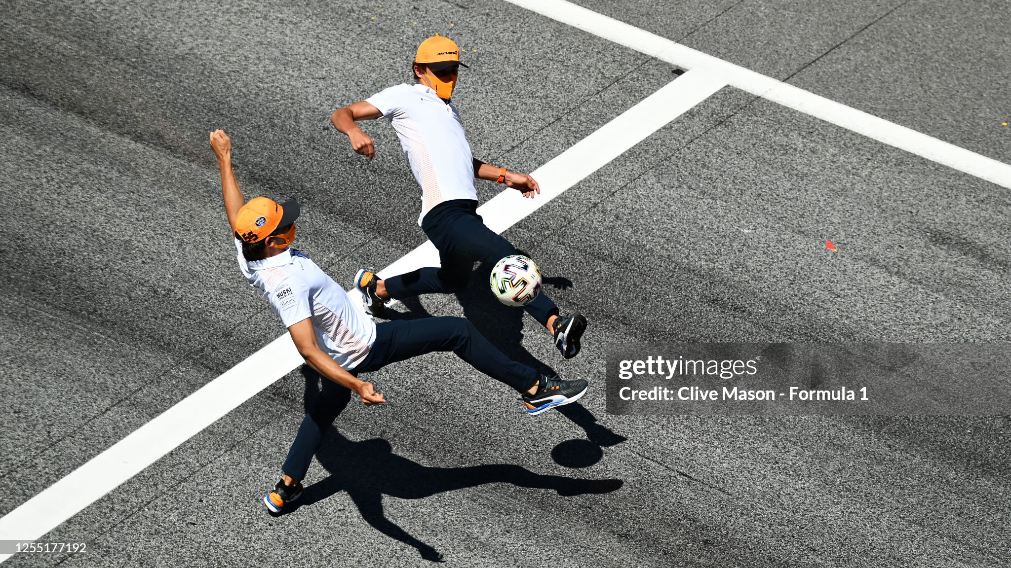 Lando Norris of Great Britain and McLaren and Carlos Sainz of Spain and McLaren play football on the start finish straight during previews for the F1 Grand Prix of Styria at Red Bull Ring on July 09, 2020 in Spielberg, Austria. 