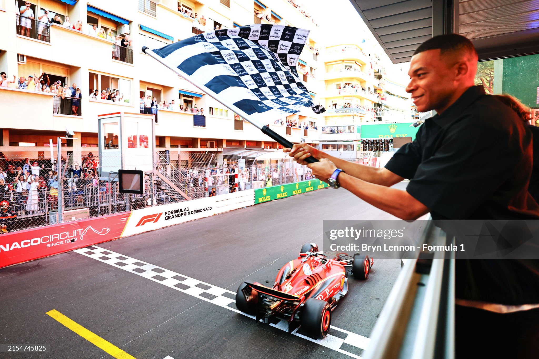 Race winner Charles Leclerc driving the Ferrari SF-24 takes the chequered flag waved by Kylian Mbappe during the F1 Grand Prix of Monaco at Circuit de Monaco on May 26, 2024. 