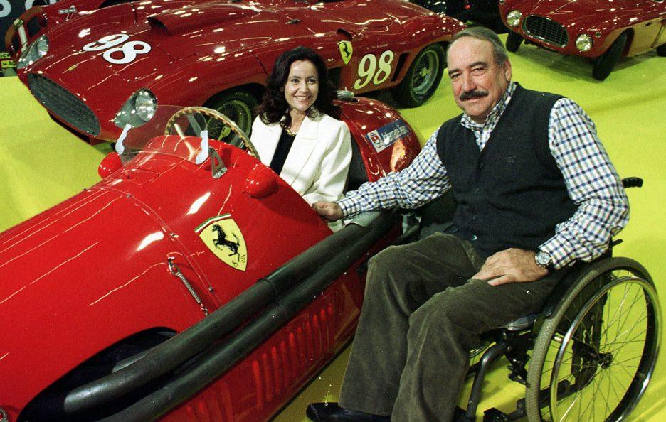 Clay Regazzoni on a wheelchair with a girl and a vintage red Ferrari.