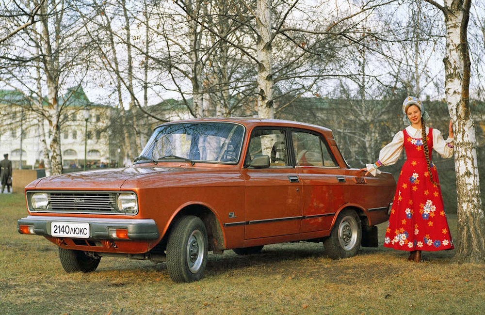 A girl in traditional dress and a red Moskvich 2140 in 1976.