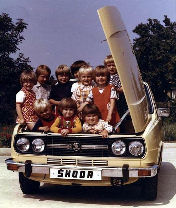 Many children in the front hood of a Skoda.