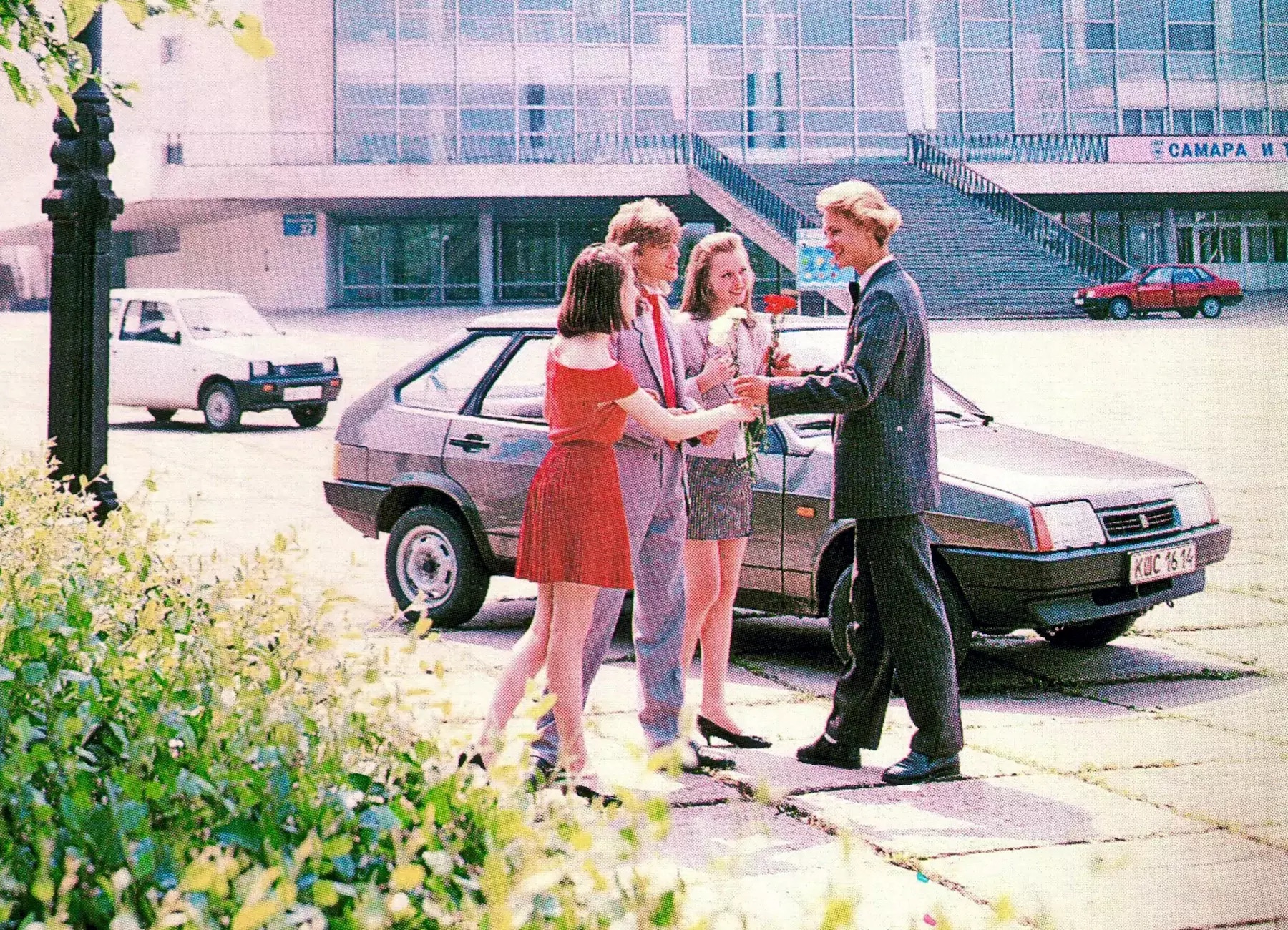 Two boys and two girls in front of a Soviet car.