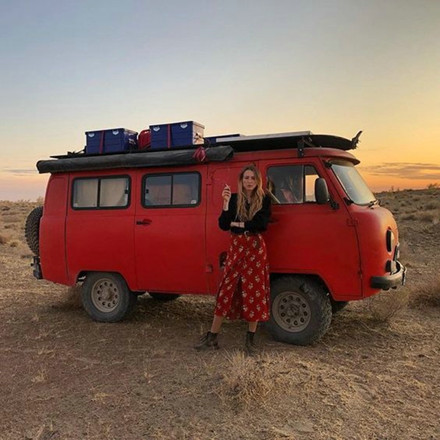 A girl in front of a red UAZ 452.