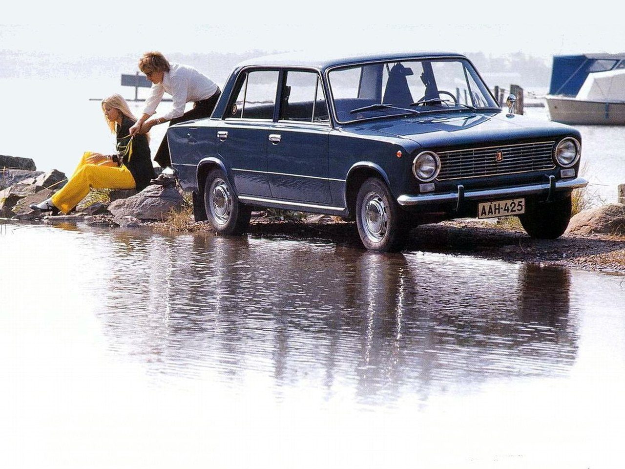 A couple and their Lada relax by the water.