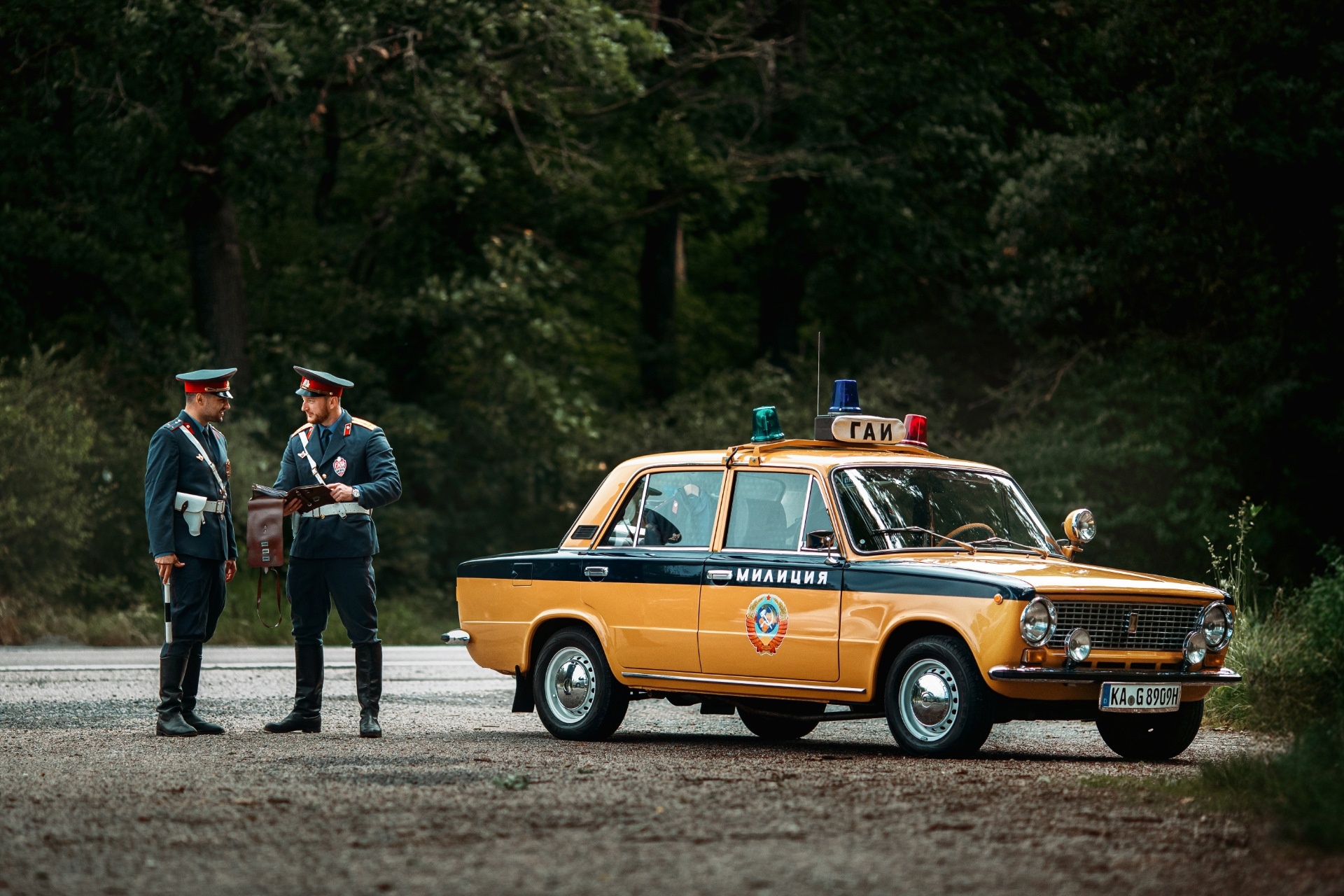 An orange Zhiguli police car and two policemen.