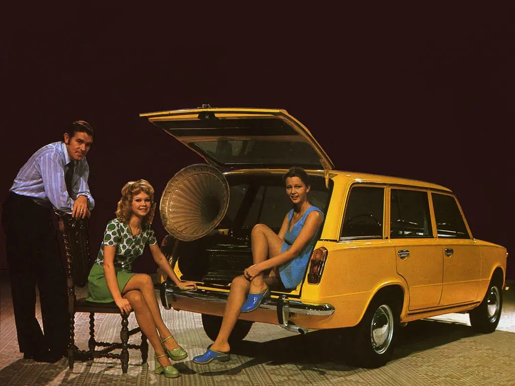 Two girls and a man with a yellow Lada 2102.