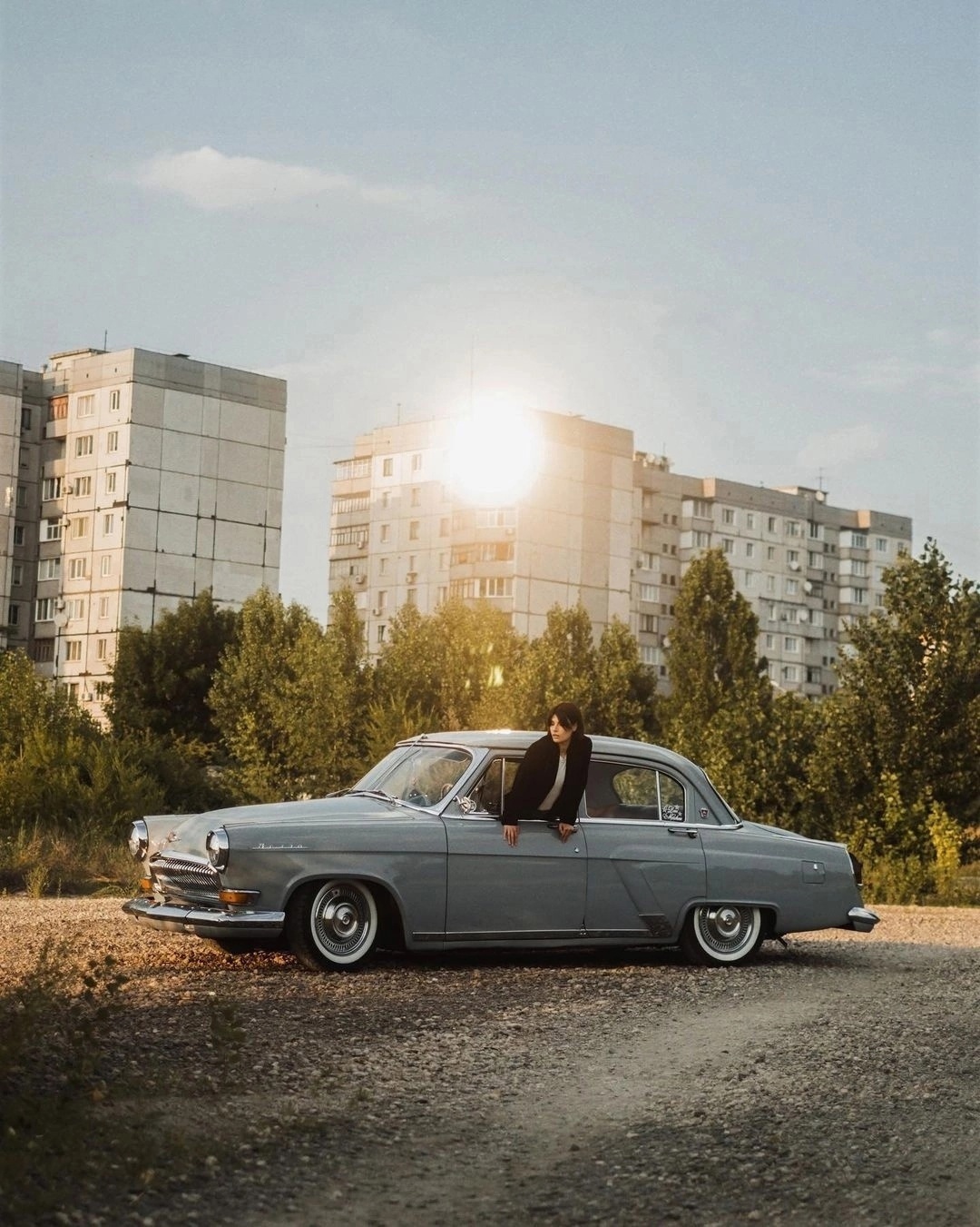 A girl in a grey Volga GAZ M-21.