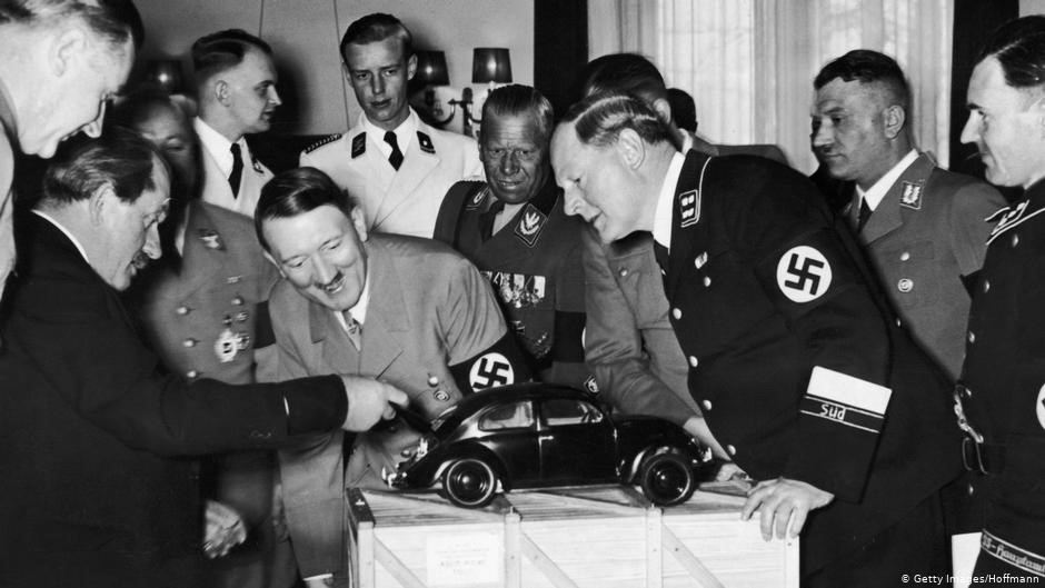 Ferdinand Porsche showing a model of the Volkswagen Beetle to Adolf Hitler in 1935.