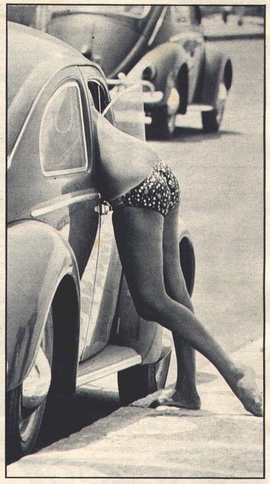 A woman in a bikini in a Beetle.