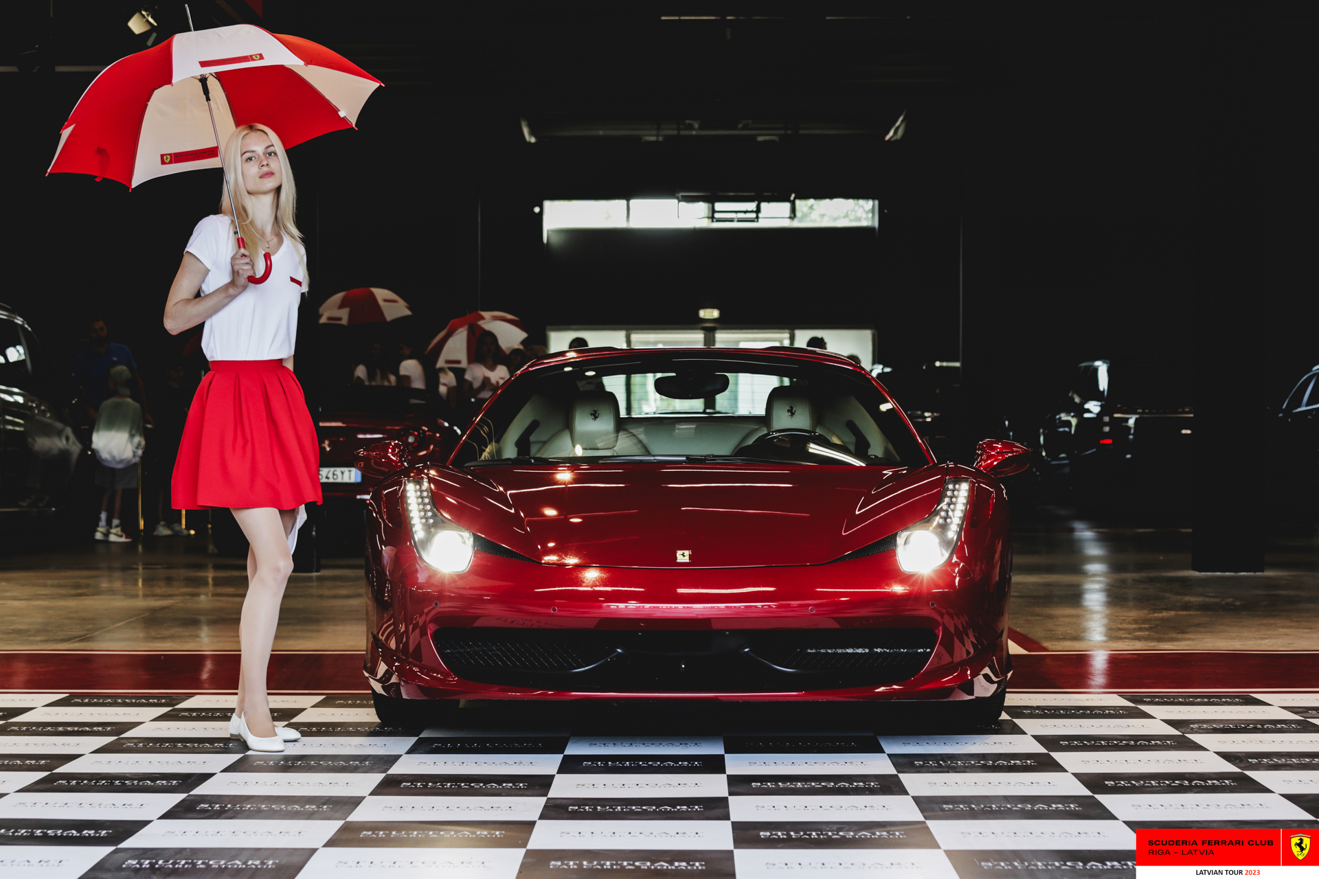 A grid girl and a red Ferrari ready to start the tour. 