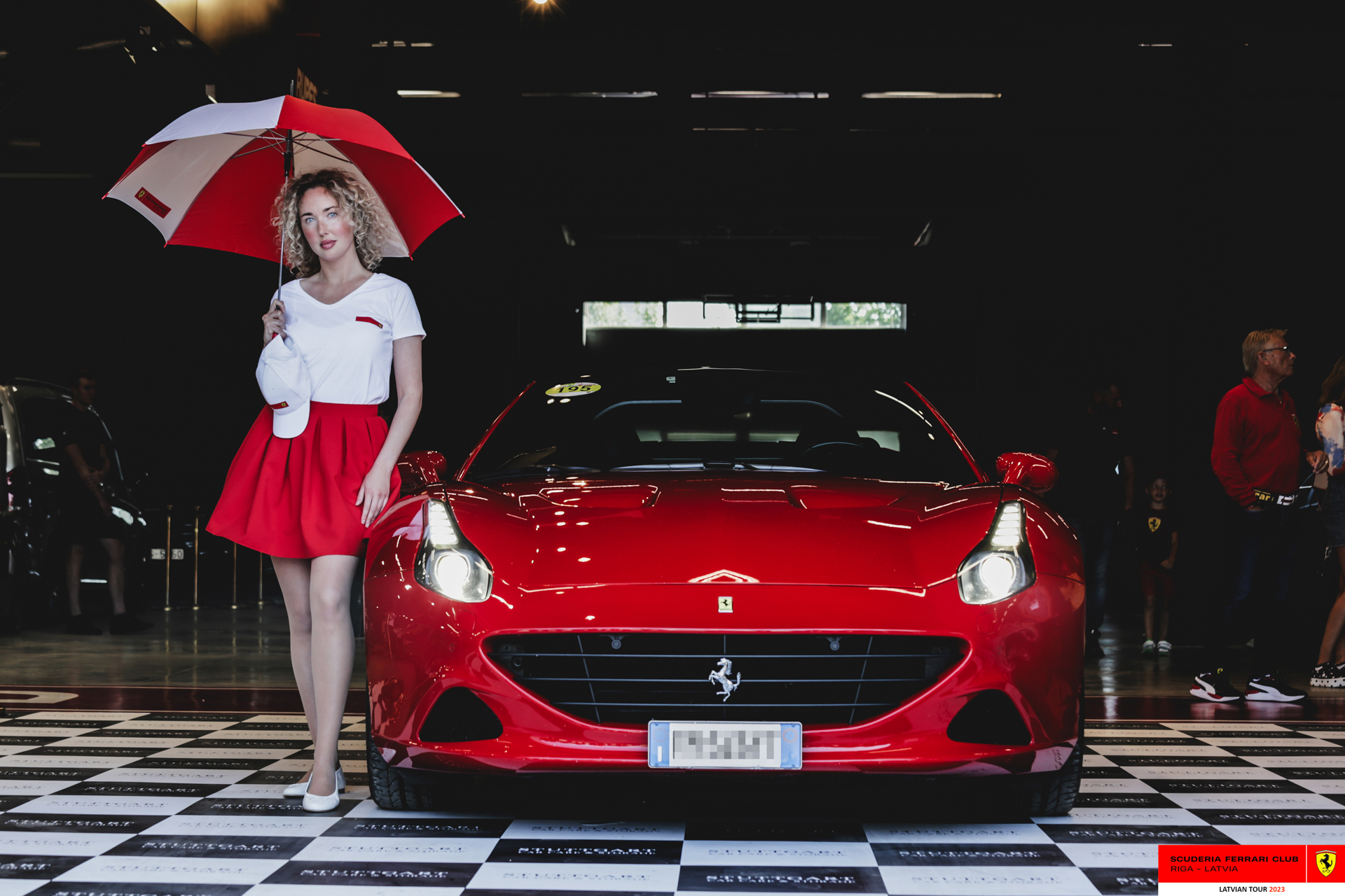 A grid girl and a red Ferrari ready to start the tour.