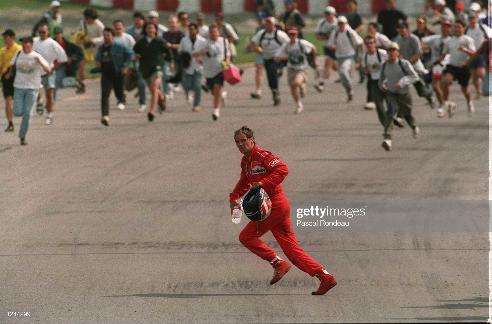 Gerhard Berger runs across the track back to the pits at the Canadian Grand Prix in Montreal as the crowd rushs forward to celebrate with Ferrari winner Jean Alesi on 11 June 1995. 