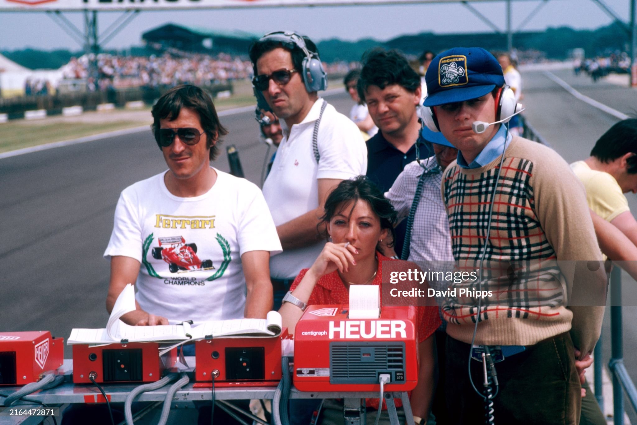 The Ferrari team follow the progress from the pit wall, using the Heuer Centigraph timing mechanism. Joann Villeneuve, wife of Gilles Villeneuve, Ferrari, sits in pensive mood with Jean Campiche (SUI) of Heuer (left) and Mauro Forghieri (center). British Grand Prix, Silverstone, England, 14 July 1979. 