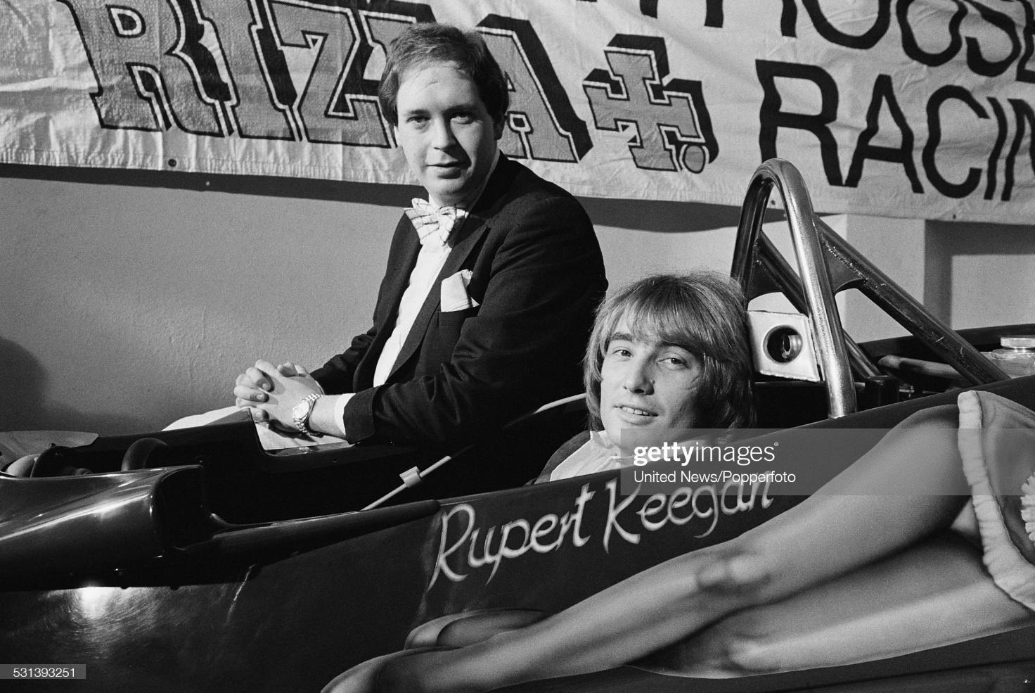 Lord Alexander Fermor-Hesketh (left) pictured with English Formula 1 racing driver Rupert Keegan sitting in the driver’s seat of a Hesketh 308E racing car featuring Penthouse Rizla Racing livery, in London on 9th March 1977.