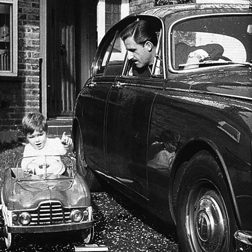 Graham Hill in a car in front of a baby.