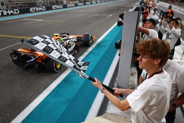 Jannik Sinner waves the checkered flag at the end of the 2025 Australian Grand Prix in Melbourne.