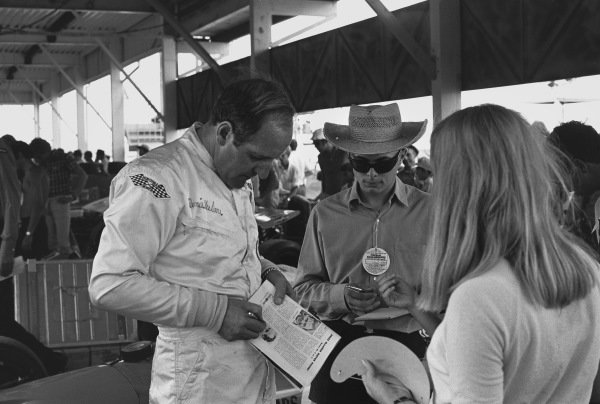 Dennis Hulme (McLaren M14A-Ford), 2nd position, signs autographs in the pits at the 1970 South African Grand Prix.