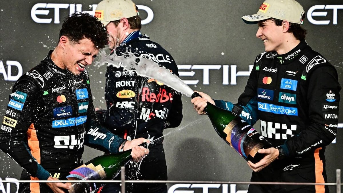 Lando Norris celebrates on the podium with Max Verstappen and Oscar Piastri.