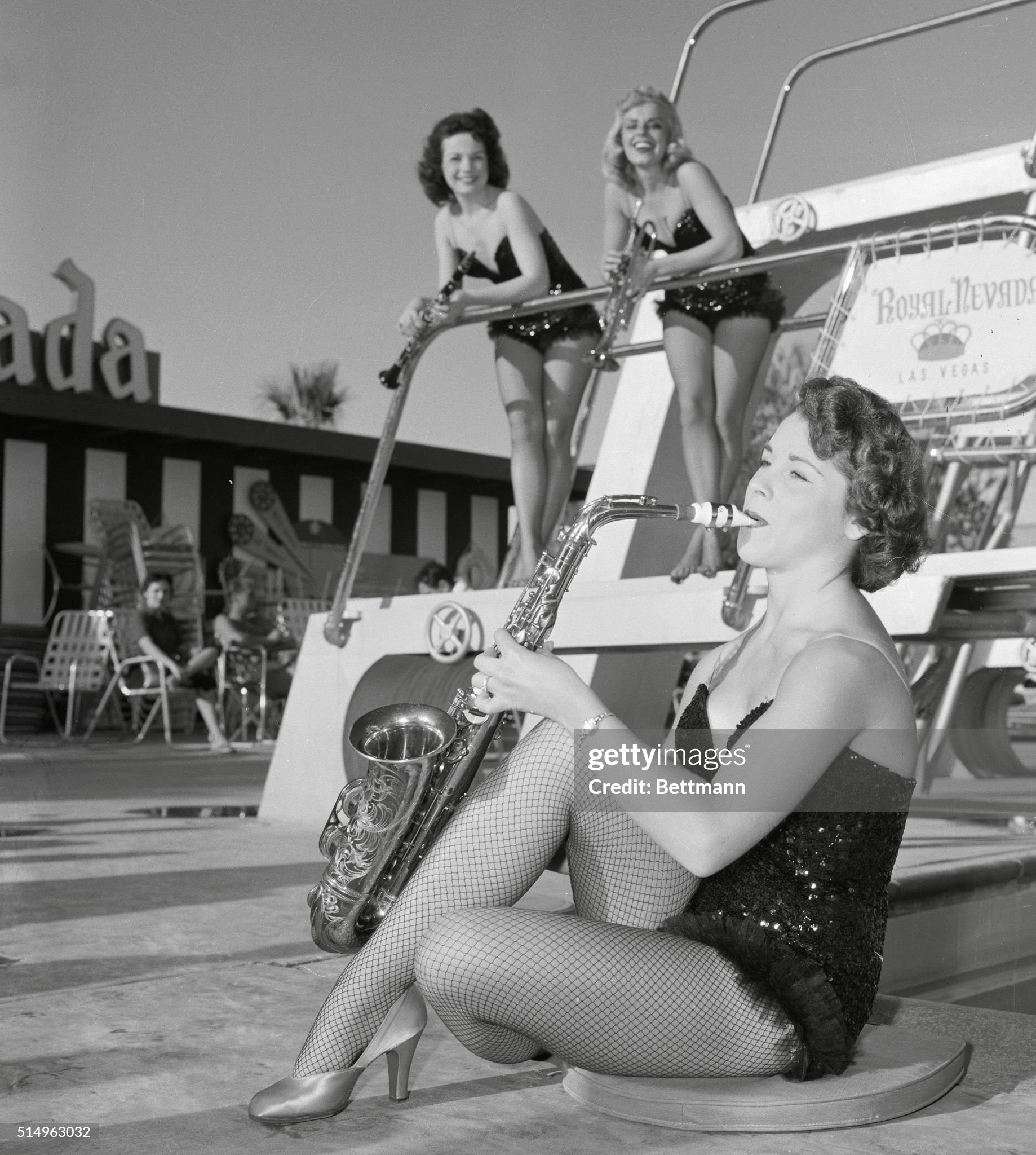 Tooting her sax in the sun at Las Vegas on 05 December 1955 is 19 year old Jessy De Roza, a member of Phil Spitalny's 20 piece all girl orchestra. Looking on as Jessy gets in some poolside practice are Rose Marie Krous, 19 (left) and Mary Ann Mazzocia, 21. All three musical beauties are from New York City.