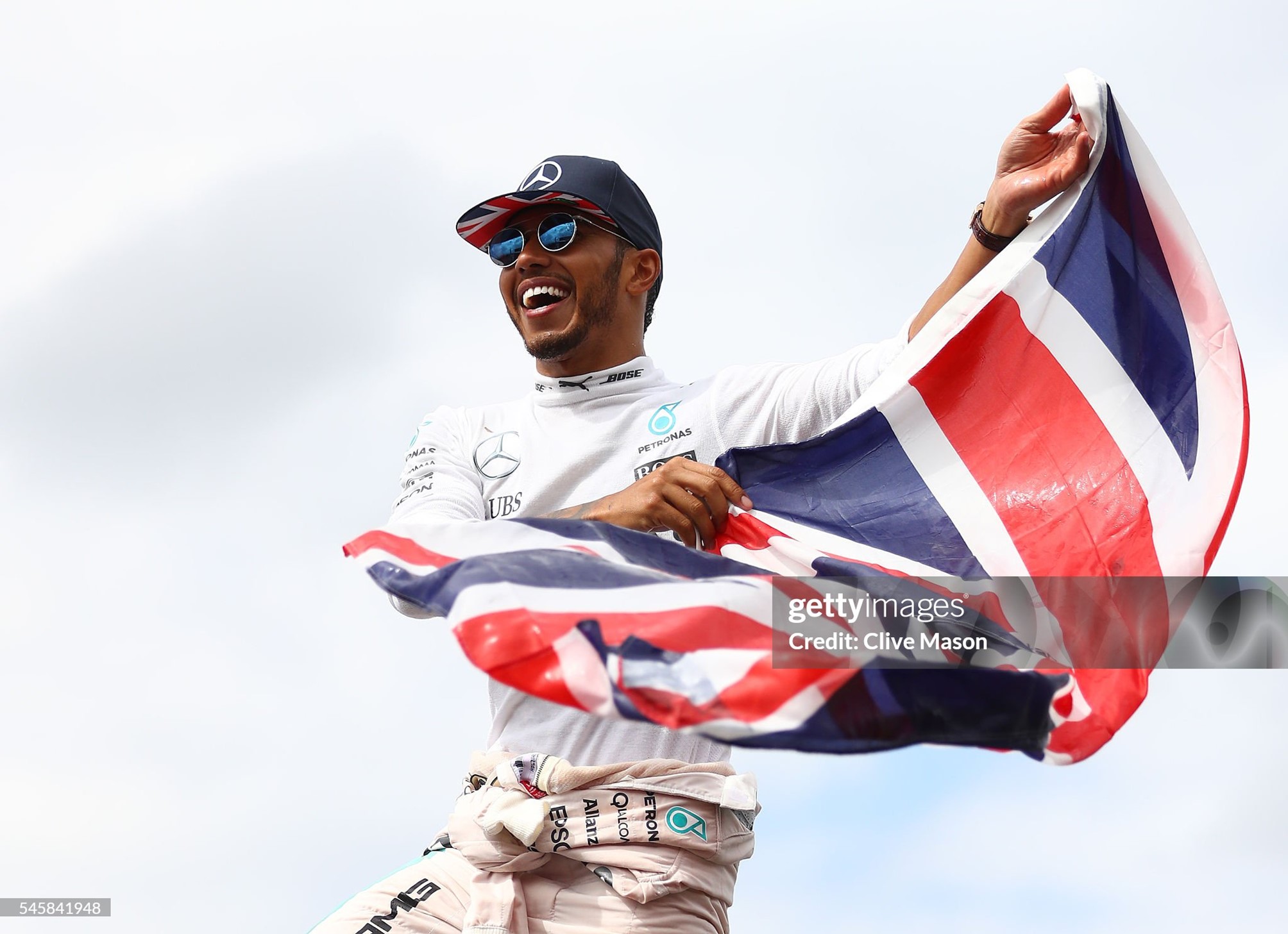 Lewis Hamilton stands on top of a fence with a Great Britain flag to celebrate his win with the British fans after the Formula One Grand Prix of Great Britain at Silverstone on July 10, 2016.