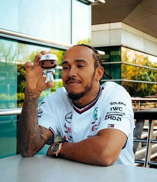 Lewis Hamilton holding a Mercedes action figure of himself.