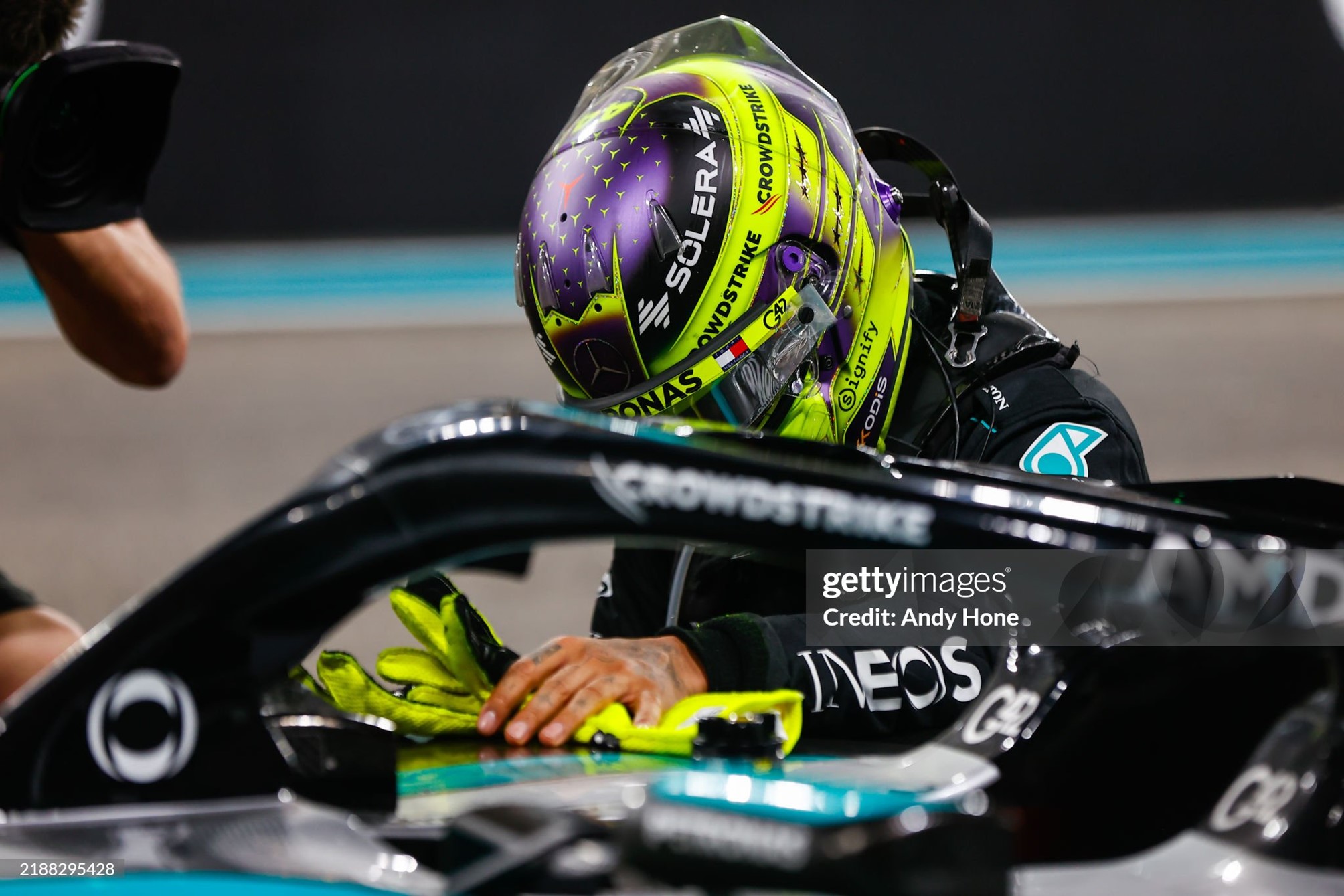 Lewis Hamilton, still wearing his helmet and with ungloved hands resting on the car, bows his head in a moving final farewell to his great Mercedes.