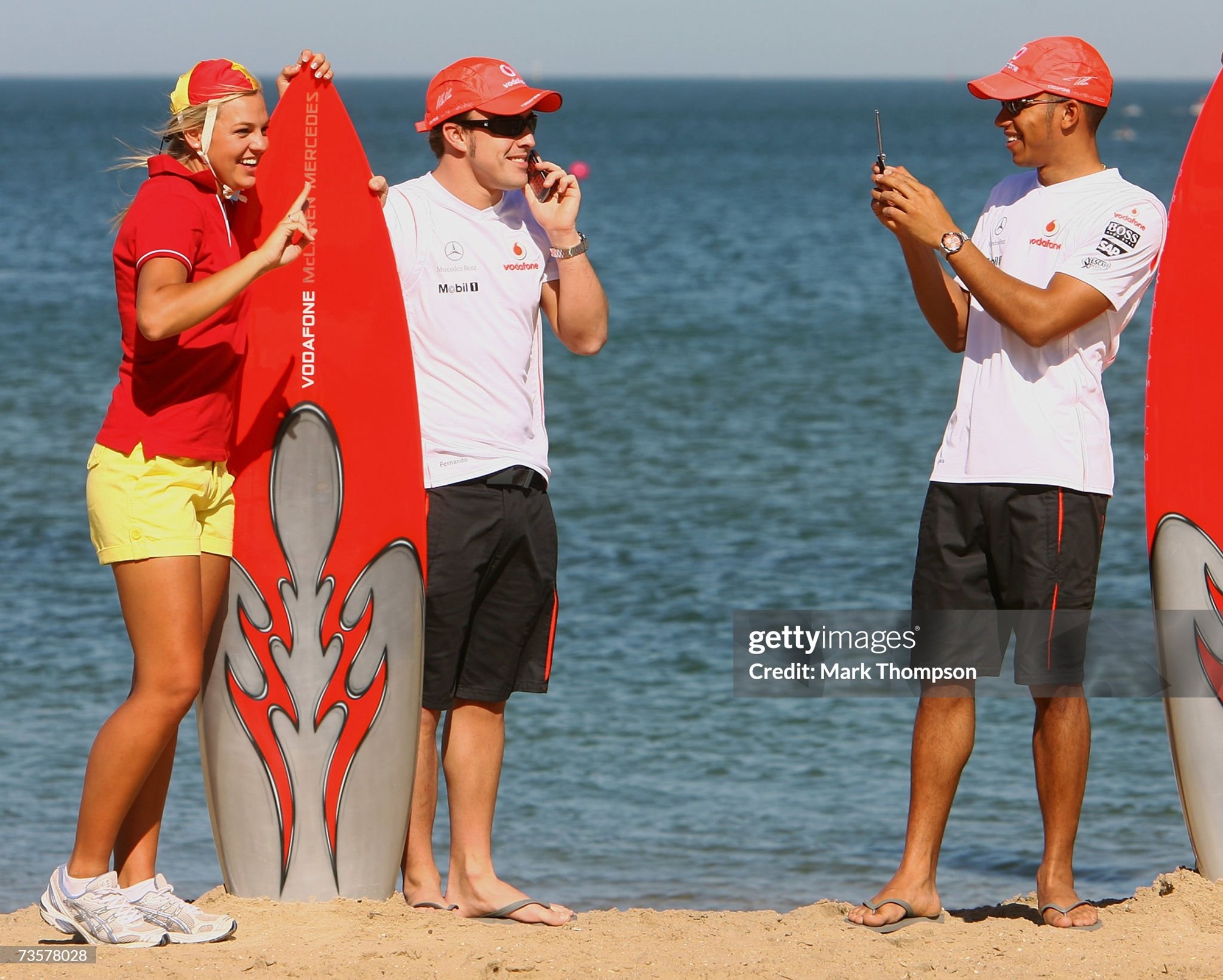 Fernando Alonso of Spain and McLaren Mercedes has his picture taken by team mate Lewis Hamilton of Great Britain as they pose with models dressed as life savers during a ‘Vodafone meet the drivers’ photocall on St Kilda Beach on 15 March 2007 in Melbourne, Australia. 