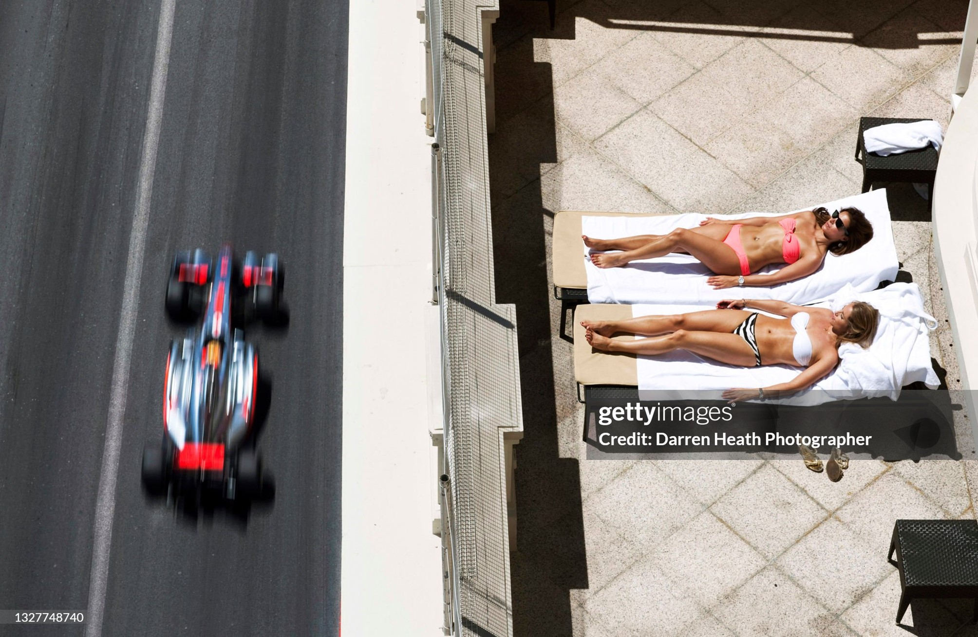 Lewis Hamilton driving his McLaren MP4-26 at speed past two attractive women sunbathing on a terrace in bikinis during practice for the Monaco Grand Prix in Monte Carlo on 28th May 2011. 