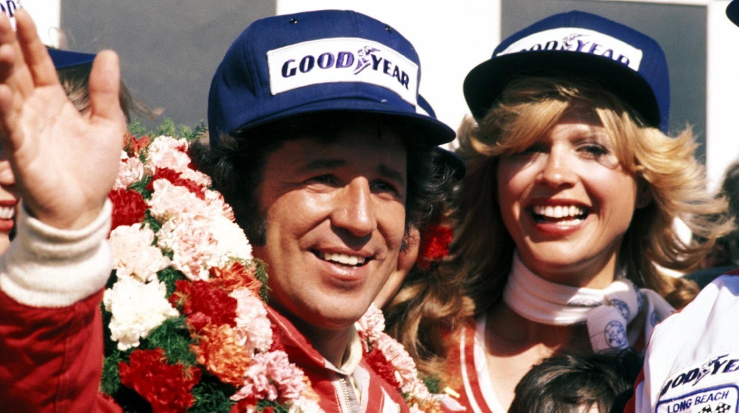 Mario Andretti on the podium with a girl.