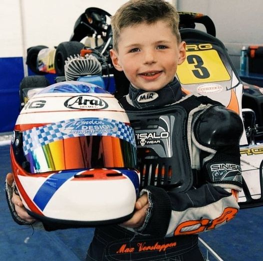 A young Max Verstappen with his helmet.