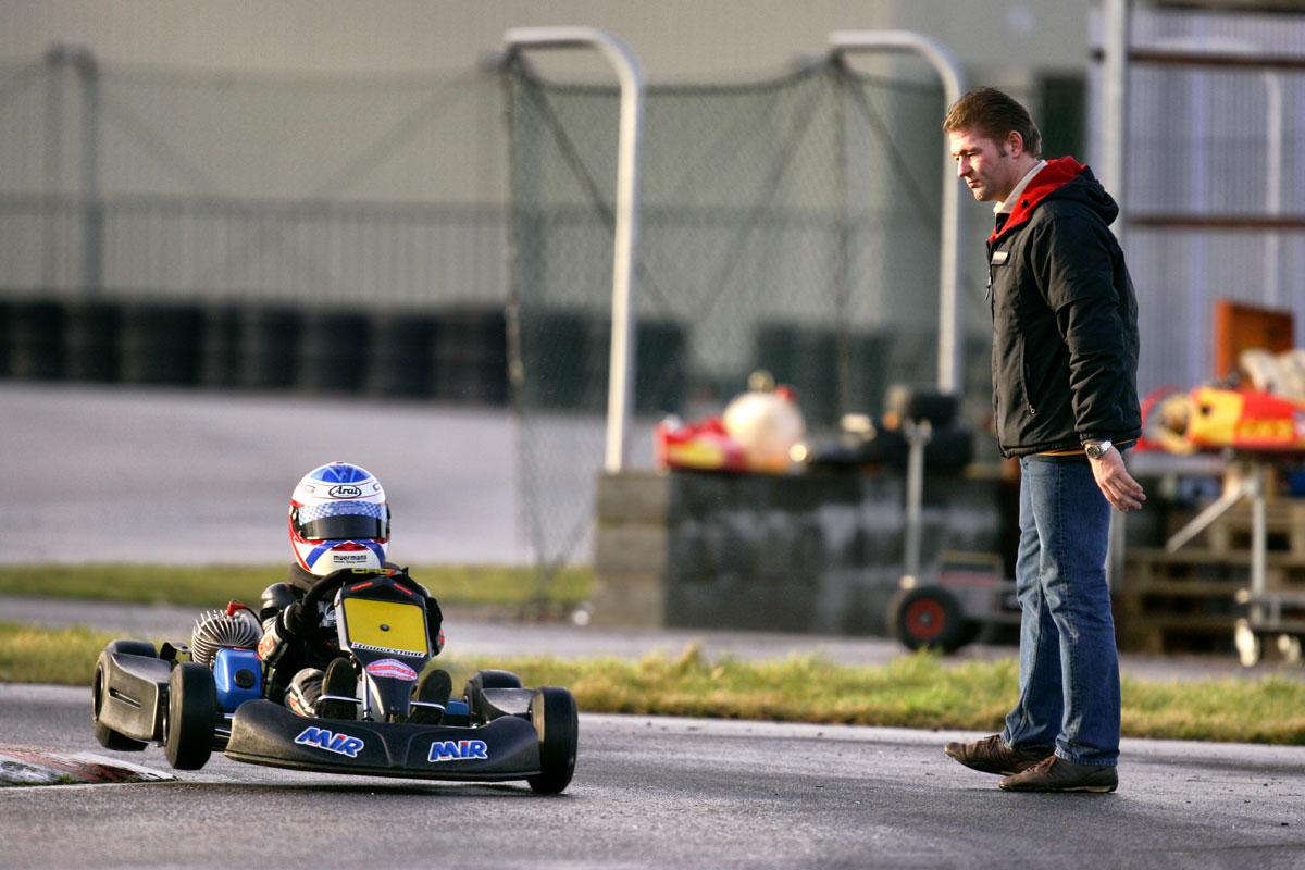 A very young Max in a kart while his father Jos is standing on the track.