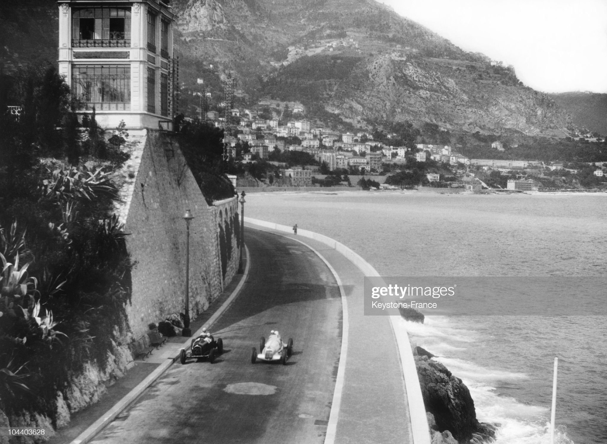 March 24, 1935, Monaco GP. The Italian race car driver Luigi Fagioli in a German car overtaking a competitor on a road along the sea. This race is taking place in the streets of Monaco every year. 