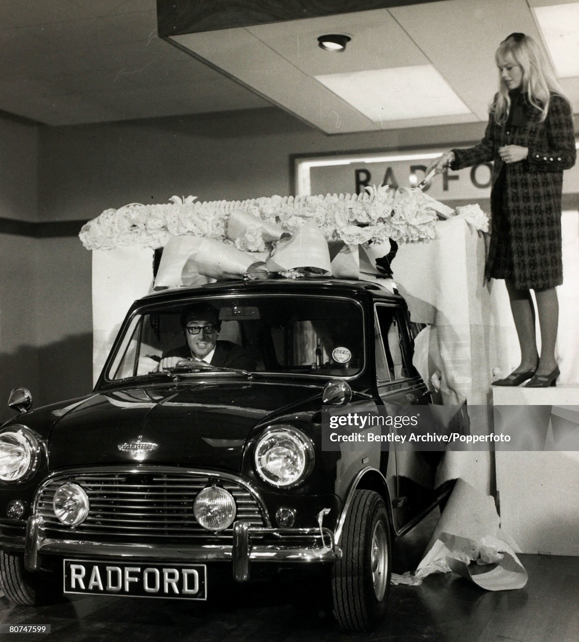 British actor/comedian Peter Sellers drives a brand new ‘Mini’ car through a fake cake as his wife Britt Ekland ‘cuts the cake’.