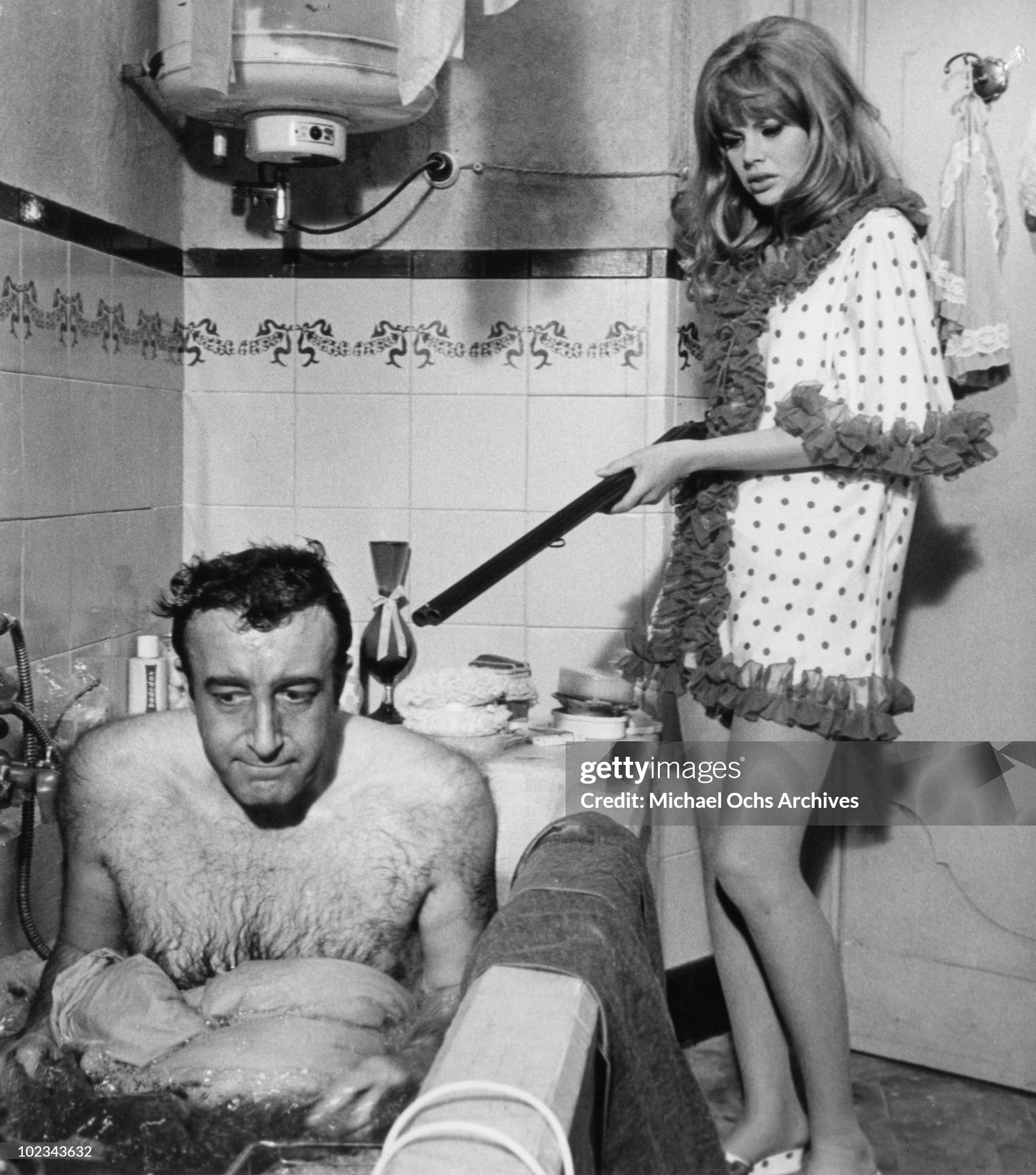 Olimpia Segura (Britt Ekland) points a shotgun at Juan Bautista (Peter Sellers) forcing him to dye himself blue in a bathtub in a scene from the movie The Bobo which was released in 1967.