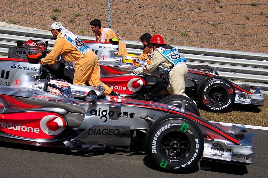 Whilst Hamilton's car is being pushed back by marshals, Alonso passes at pitlane exit at the 2007 Turkish Grand Prix in Istanbul. 